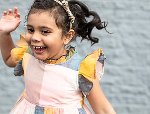 Gabby is smiling and laughing in her Jennifer Dress against a grey brick wall. Click to read the full interview with Gabby.