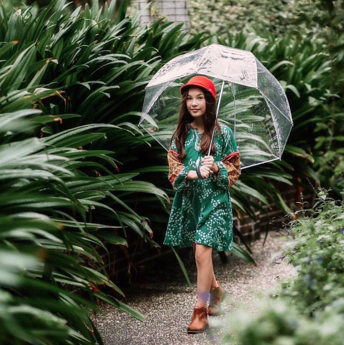 Pink Chicken customer in a long sleeve dress walking with an umbrella