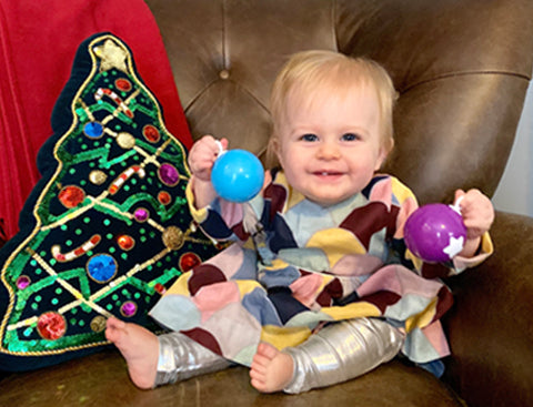 Violet in her baby Amma dress, surrounded by Christmas decor. Click to read the full interview with Violet.