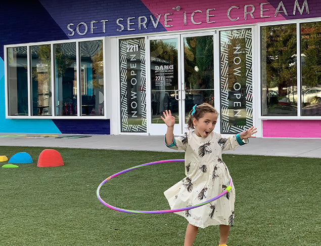 Lucille from Denver hula-hoops in front of the soft serve ice cream parlor in her unicorn Pink Chicken dress. Click to the full interview.